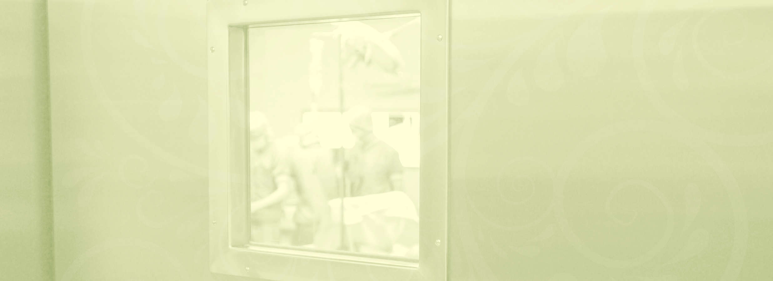 Symbolbild. Blick durch ein kleines Fenster in einer Tür in einen Operationssaal.